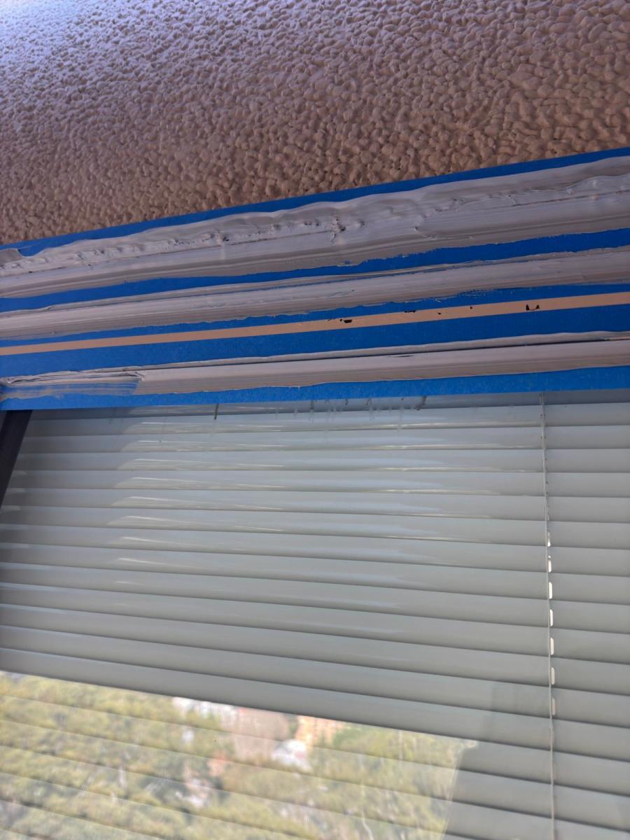 Rope access caulking work showing blue painter&#039;s tape and weathered window sealant requiring maintenance