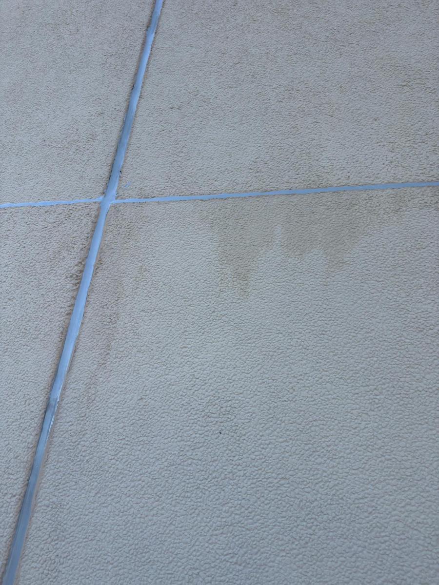 Close-up view of rendered building facade with blue sealant lines between concrete panels