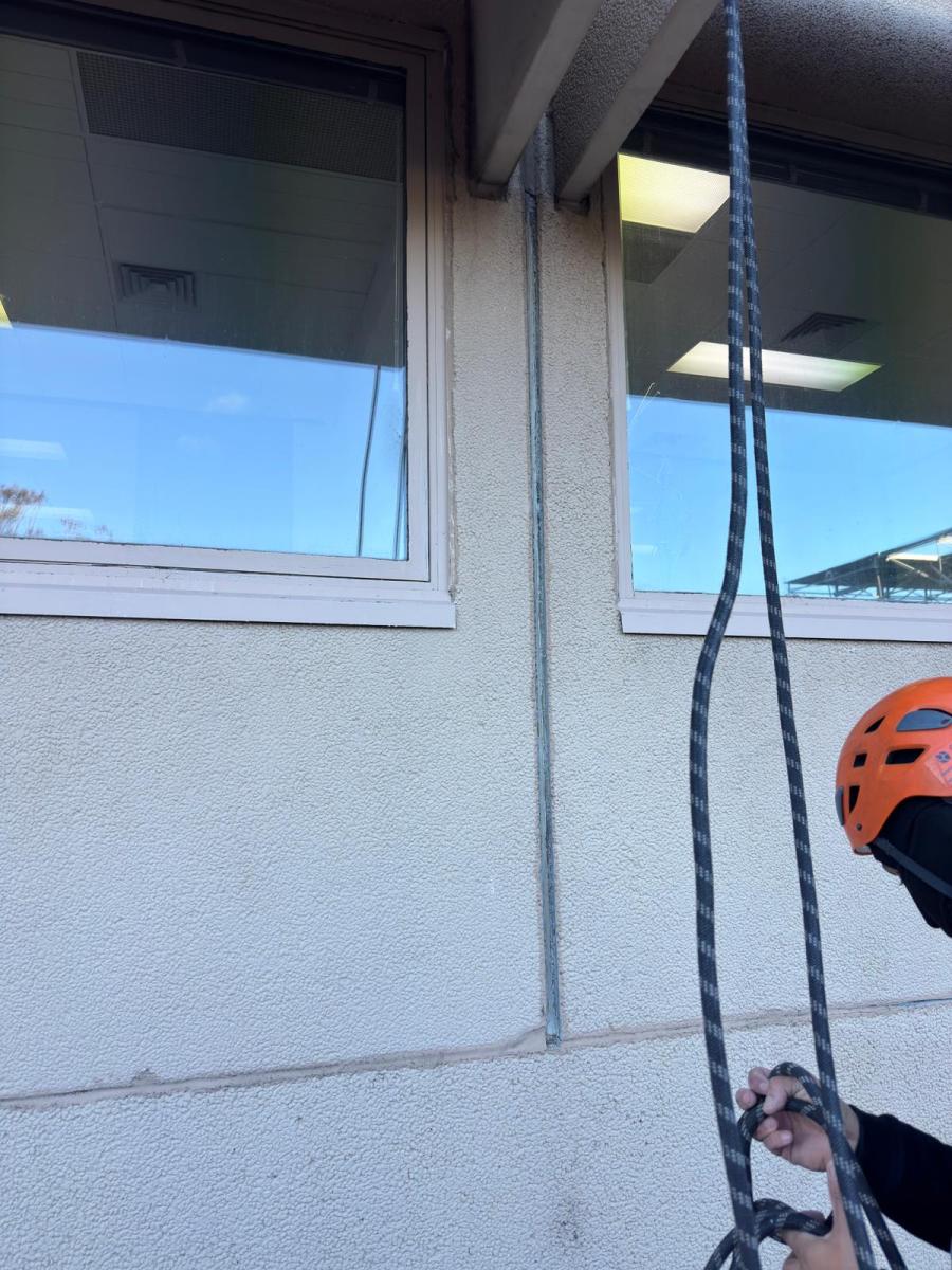 Rope access technician&#039;s view whilst abseiling down commercial building facade for maintenance work
