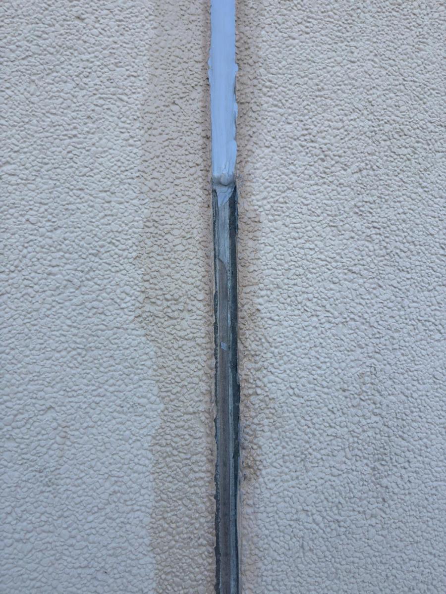 Damaged caulking and sealant on white rendered building facade showing weathered deterioration