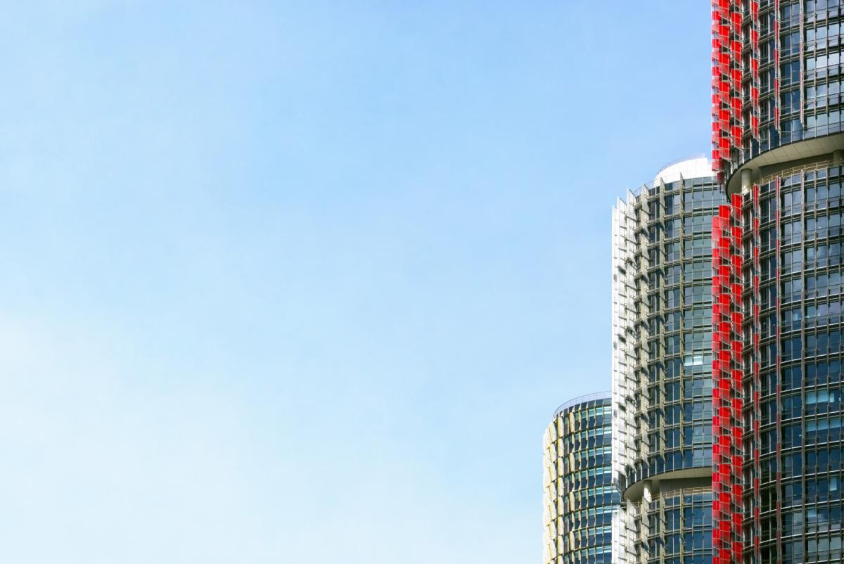 Modern high rise buildings with glass facades and red architectural elements against clear blue sky