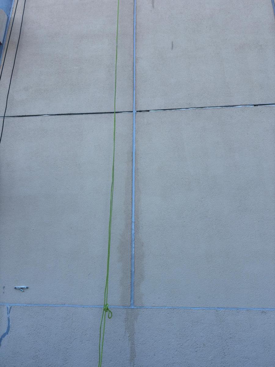 Close-up of modern building facade showing concrete panels with green and blue rope access safety lines