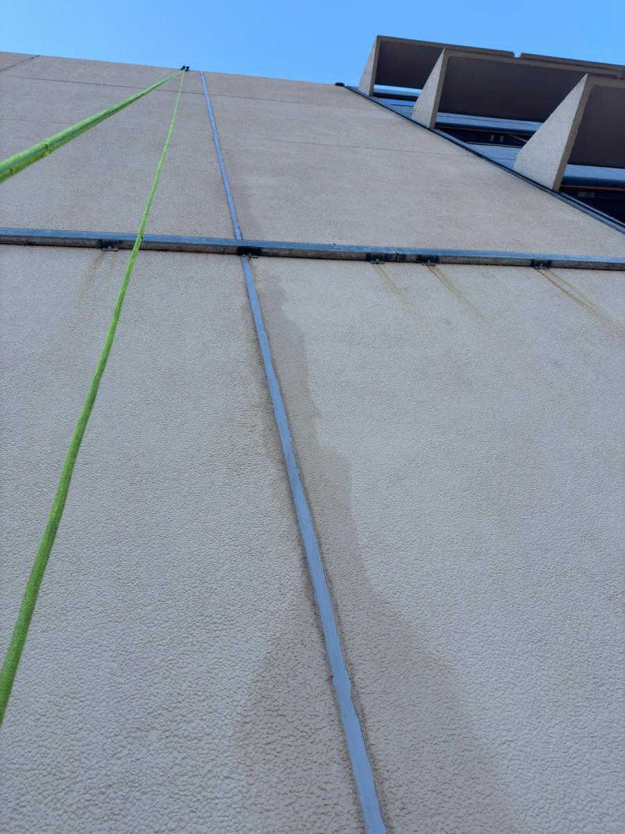 Rope access lines on concrete building facade showing professional height safety equipment for high-rise maintenance